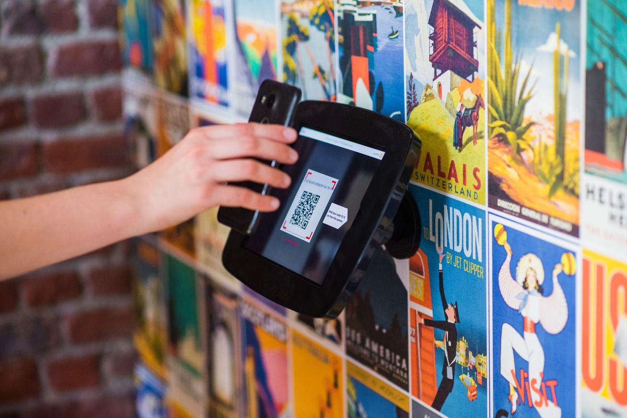 Hand scanning a real estate QR code on a yard sign with property posters behind