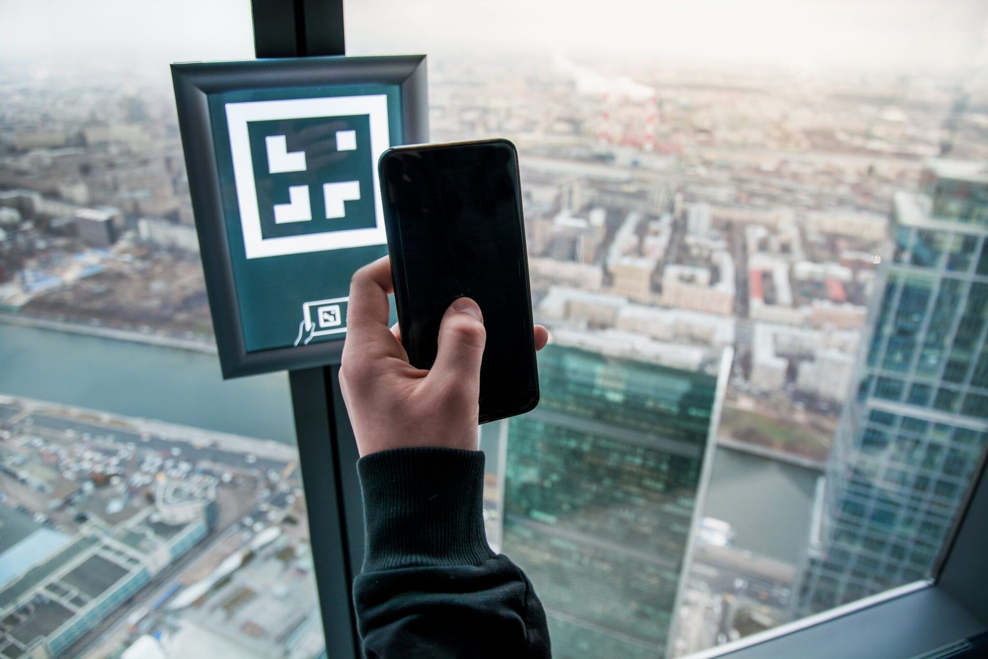 Museum visitor scanning a QR code with a smartphone inside an exhibit space