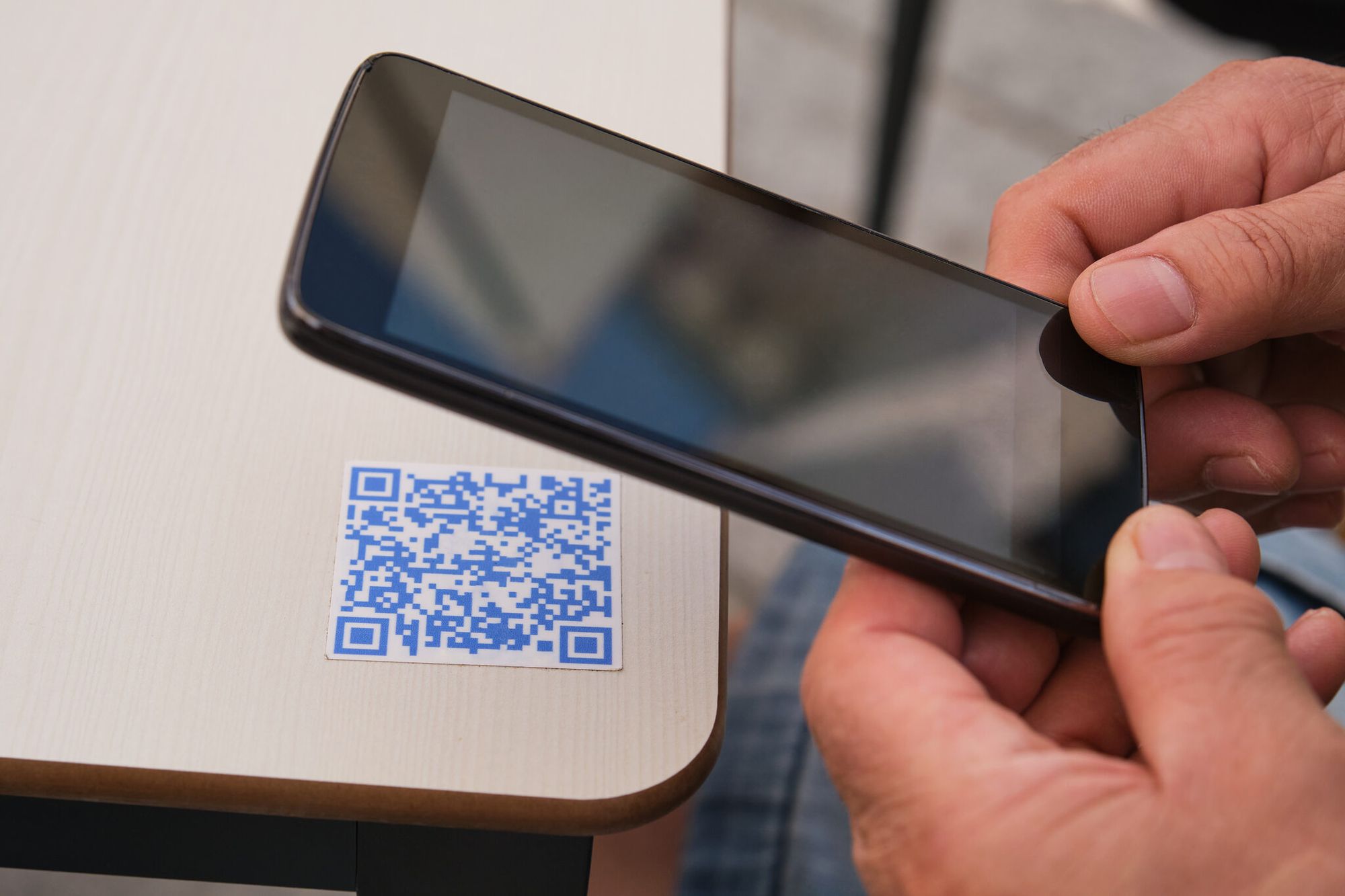 Hand using a smartphone to scan a tabletop QR code at an open house