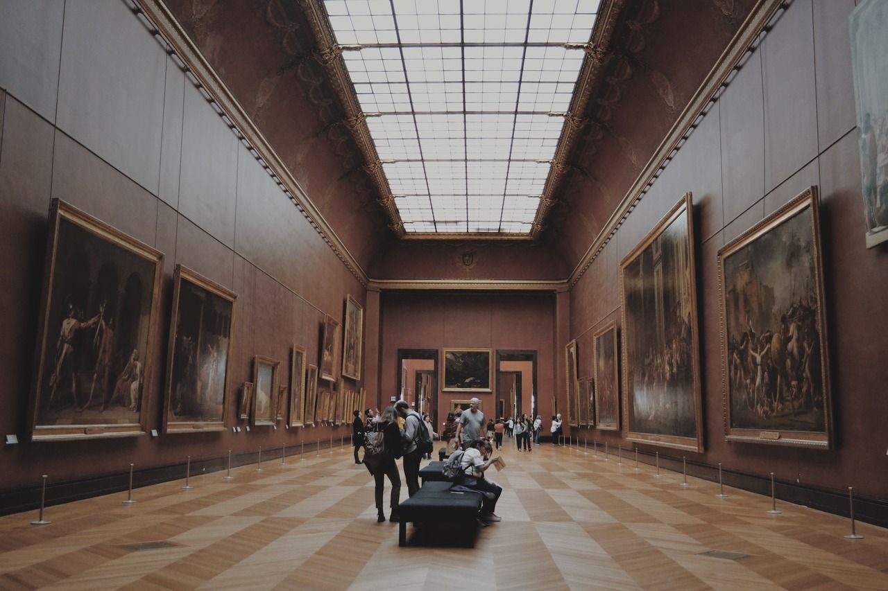 Museum visitors looking at paintings on an art gallery wall