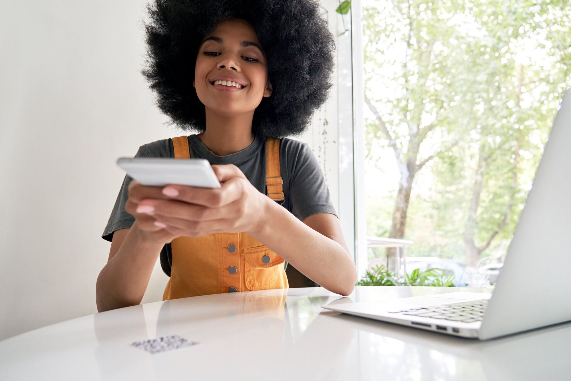 smiling lady holding a smartphone and scanning a QR code