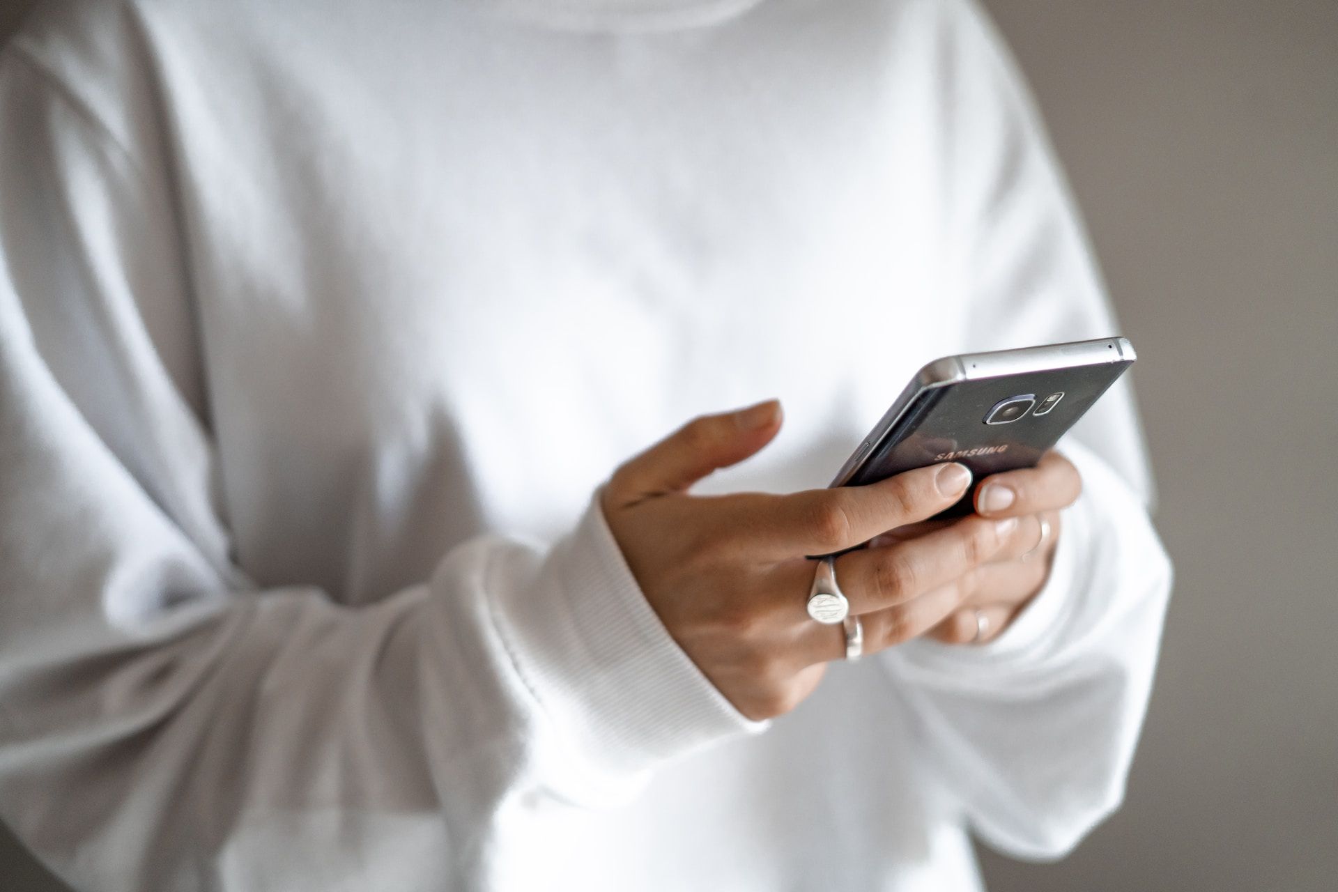 Woman in a white jumper holding a phone scanning a QR code