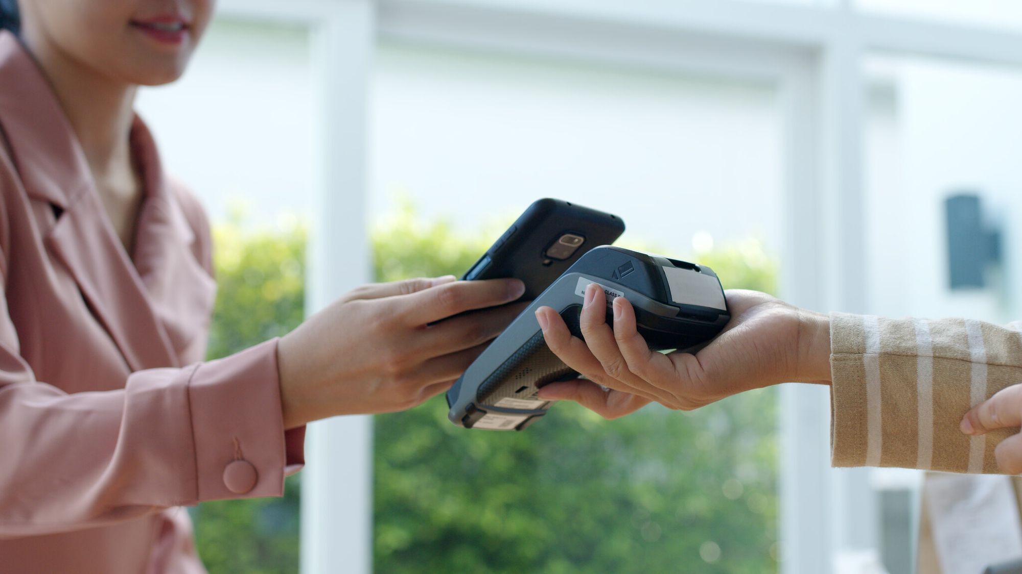 Close-up of a woman scanning a QR code at a retail checkout for payment