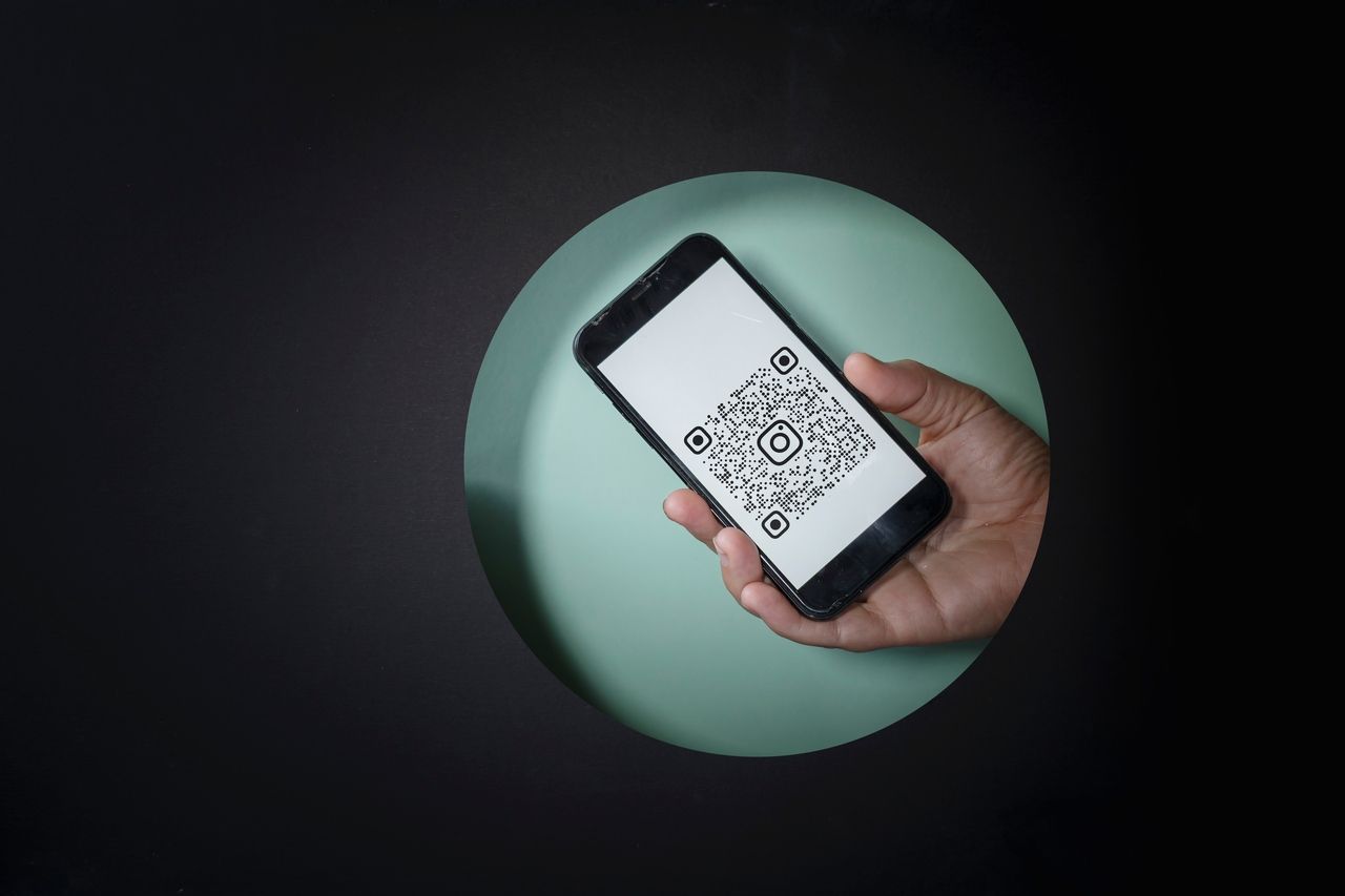 smartphone displaying a postcard QR code with social media logo