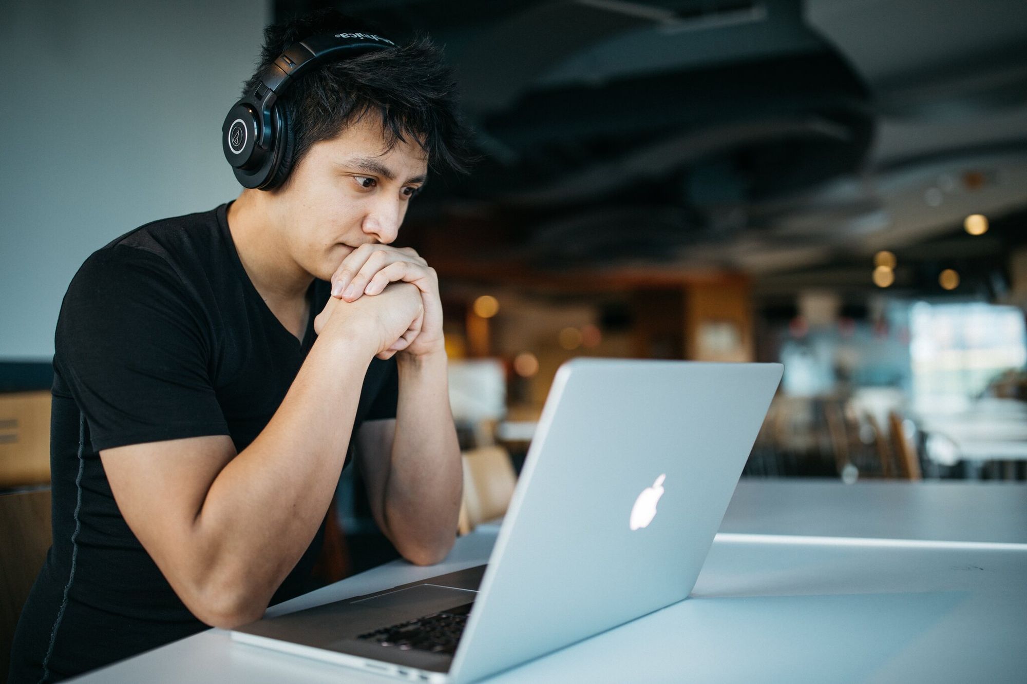 A man wearing headphones and checking a laptop screen for QR scan analytics