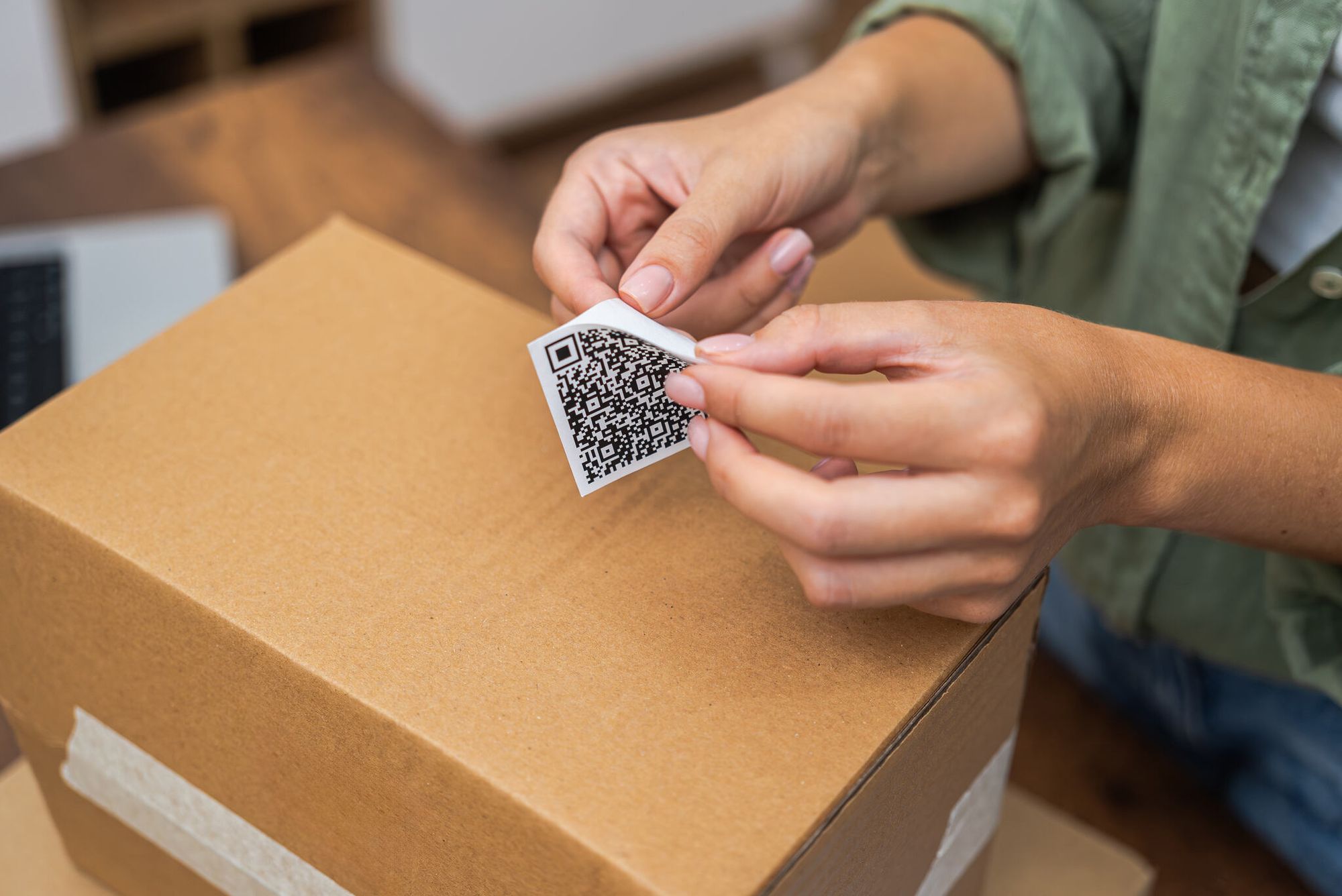 Woman's hands placing a QR code verification sticker on a package
