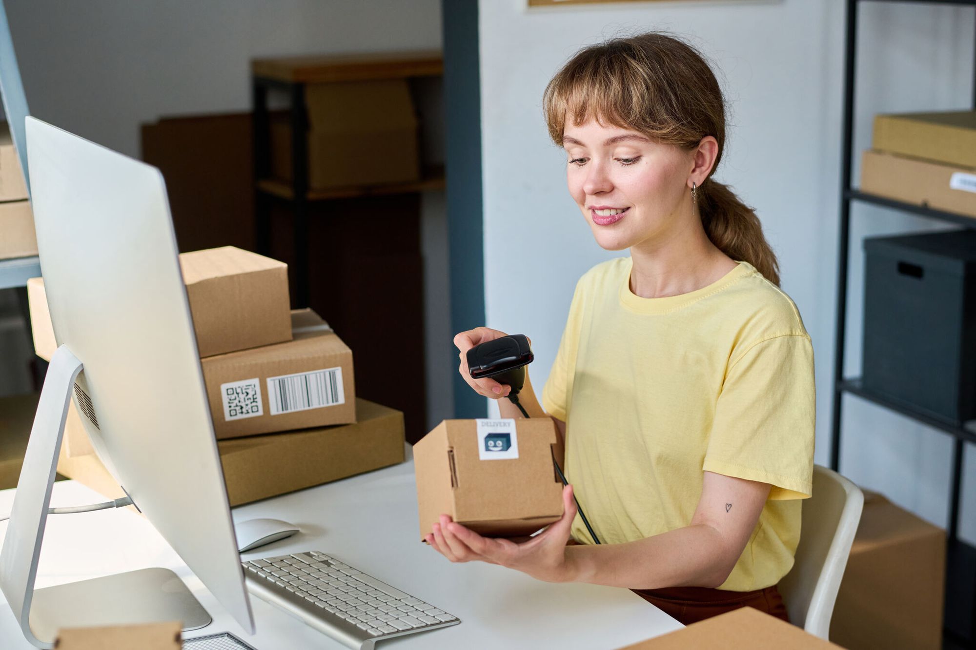 A young smiling woman scanning a packed box with a QR code on a certificate