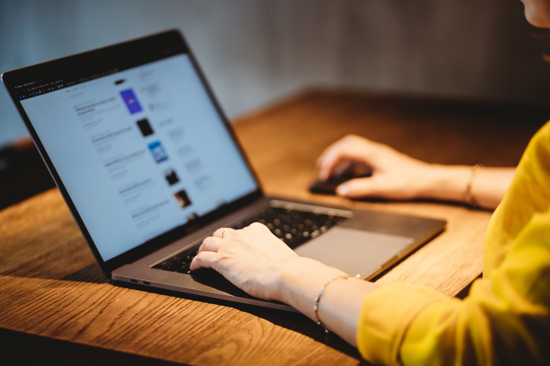 person using MacBook Pro on brown wooden table