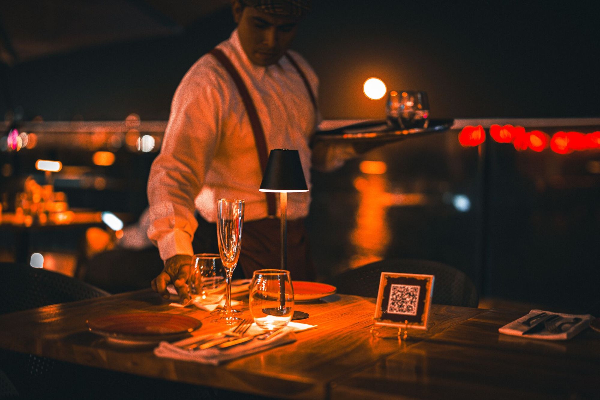 a waiter setting the table with a QR code