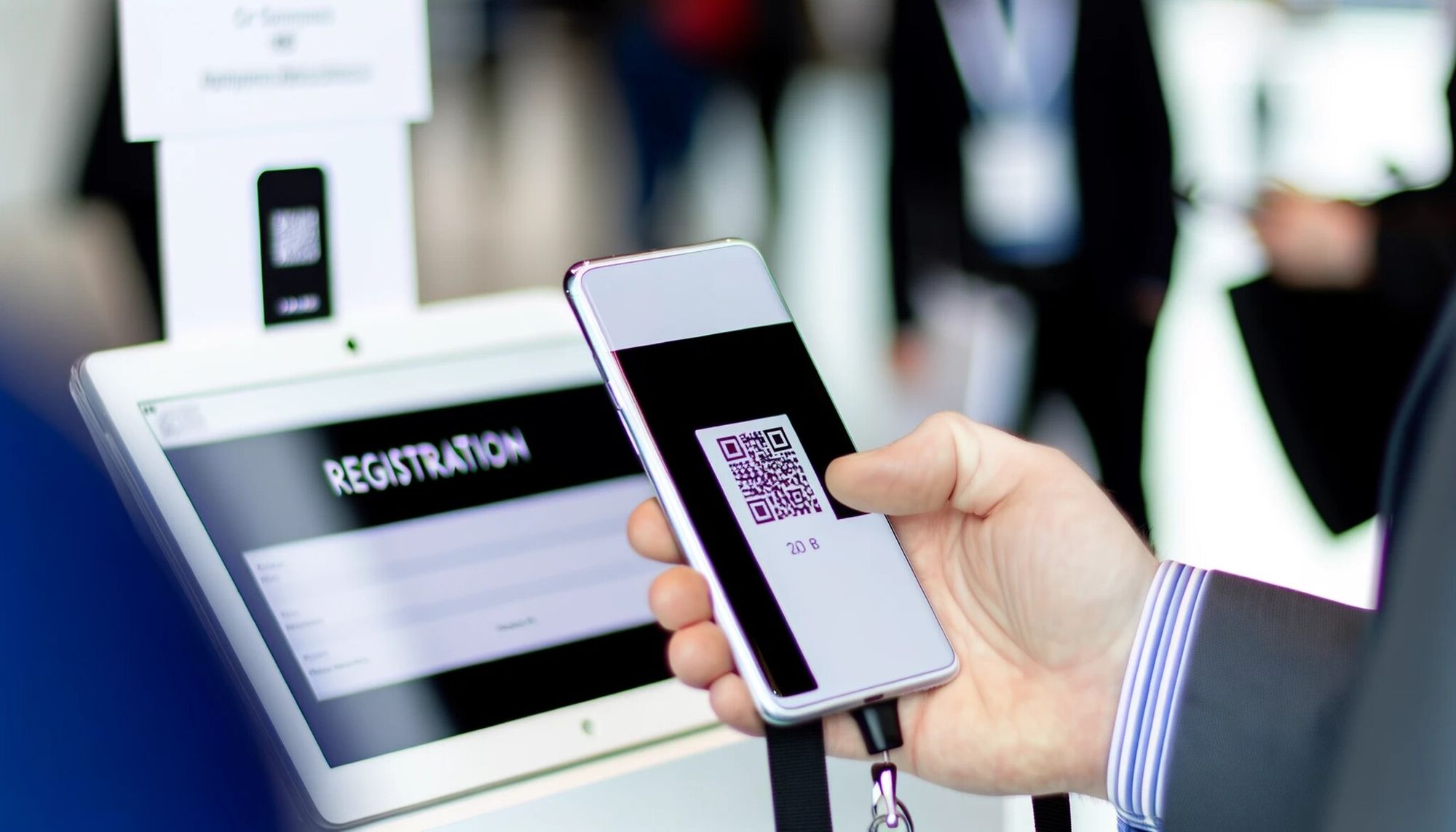 A close-up view of a person's hand holding a smartphone, and scanning a QR code for registration