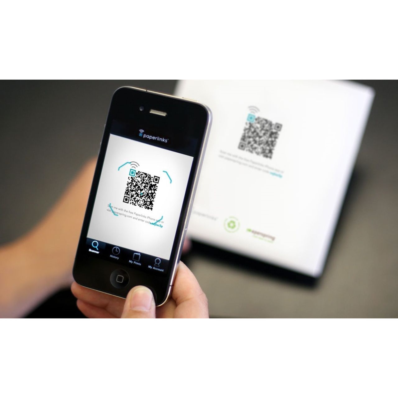 iPhone camera framing a printed QR code with the yellow detection box visible