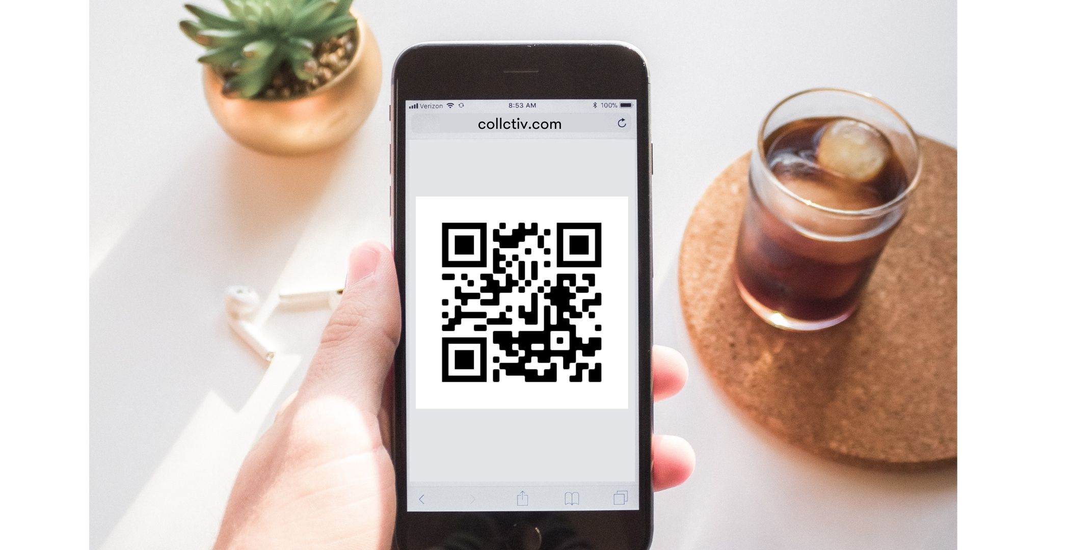an iPhone displaying a QR code and a glasses and a plant at the background